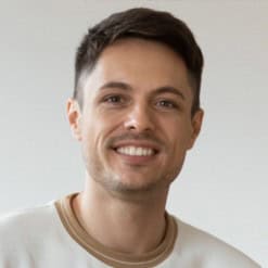 Smiling young man with short dark hair and casual white shirt.