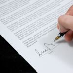 Person signing a document for car shipping and auto transport services.