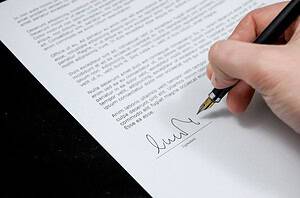 Person signing a document for car shipping and auto transport services.