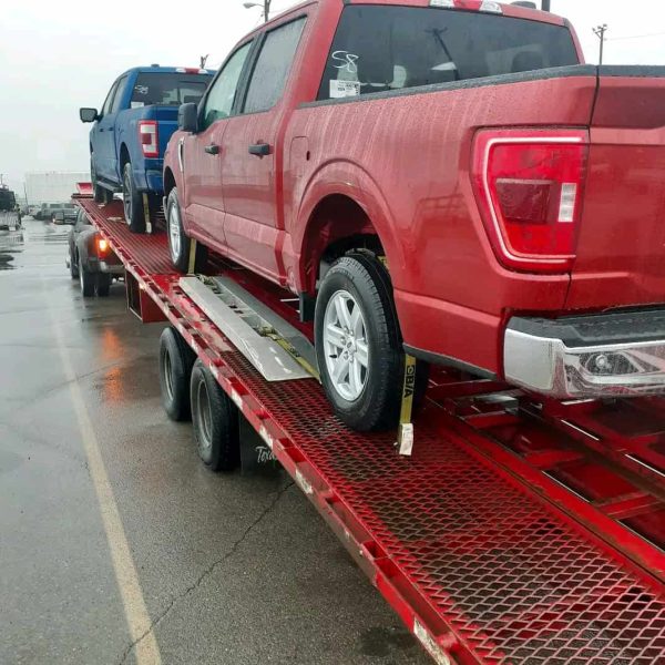 Red pickup truck on car carrier for auto transport service.