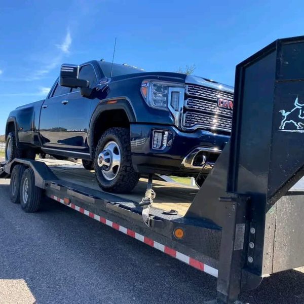 Black GMC pickup truck on a flatbed trailer for auto shipping.