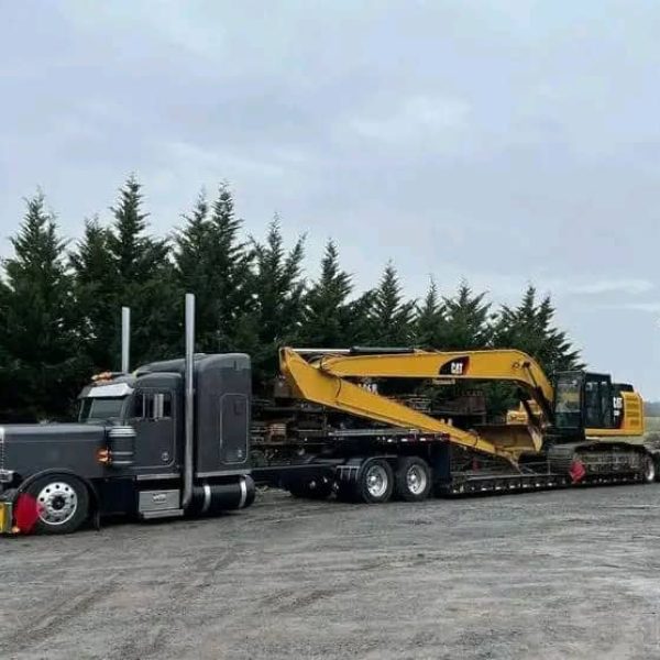 Semi-truck transporting a large excavator for auto transport services.