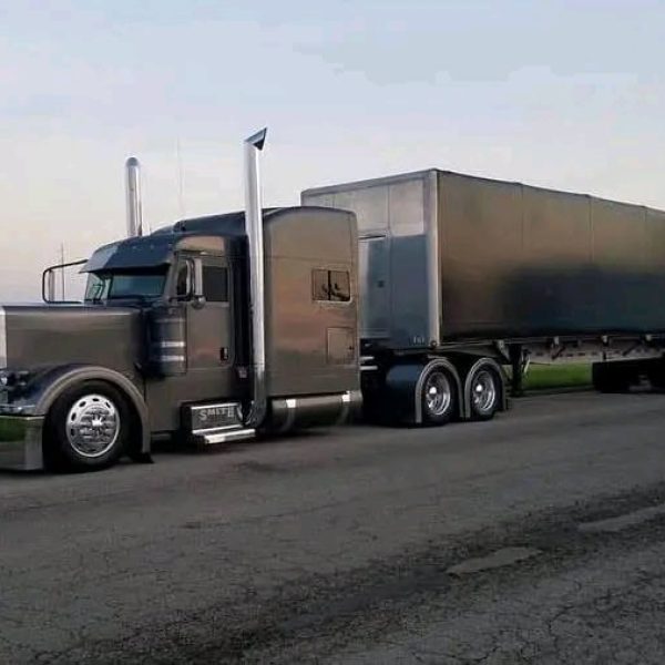 Semi truck with trailer on open road for vehicle shipping services.