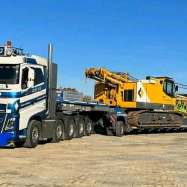 Large yellow crane loaded on a flatbed truck for transport.
