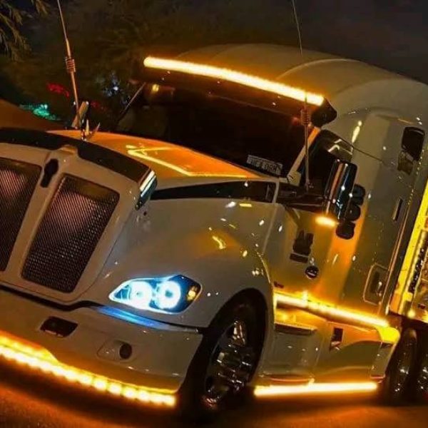 Night view of a luxury car transport truck with bright LED lights.